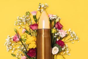 Pacifism and non-violence movement. Bullet and bunch of different flowers against yellow background. photo