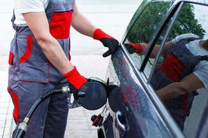 Filling station attendant filling tank of clients car photo