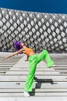 Active woman wearing colorful sportswear performing on the street during summer day photo