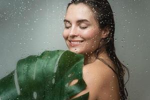 mujer joven con una piel suave que sostiene la hoja de la planta monstera deliciosa foto