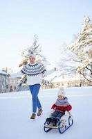 Mother and her cute little son having on a sledding hill photo