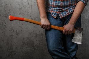 Axe in male hand over old dirty wall photo