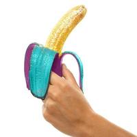 Female hands and banana covered with a colorful glitters