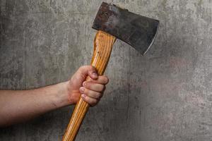 Axe in male hand over old dirty wall photo