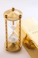 Hourglass and fine gold bullion. Concept of investment. photo