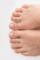 Female feet with soft skin and french pedicure on white background photo