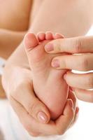 Mother massaging little child's feet and soles. photo