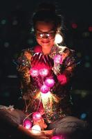 Happy woman wearing glowing jacket with sequins is holding light balls in her hands photo