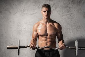 Young and muscular bodybuilder working out with a barbell photo