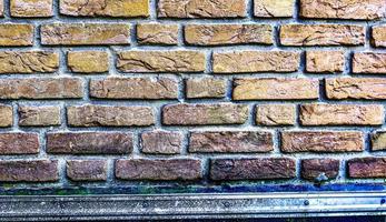 Detailed view at a colorful old and weathered brick wall texture as a panoramic background. photo