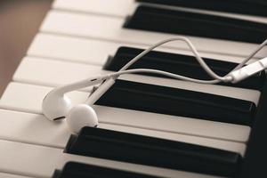 Closeup of earphones over piano or synthesizer keyboard photo