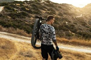 Professional downhill rider carrying his bicycle on shoulder photo