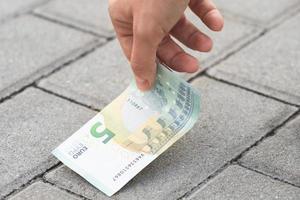 Woman is picking five euro banknote from the ground photo