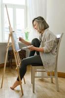 Young woman artist painting on canvas on the easel photo