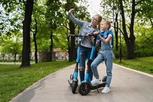feliz madre e hija tomándose selfie mientras montan scooters eléctricos foto