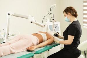 dermatólogo y cliente mujer durante el tratamiento de rejuvenecimiento cutáneo con láser en una clínica de estética médica foto