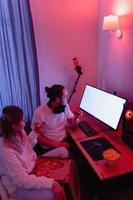 Couple chilling at home in room with neon light and eating pizza, watching movie online or playing video games photo