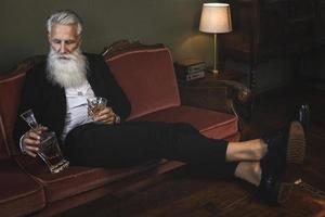 Handsome and bearded senior man drinking whiskey photo