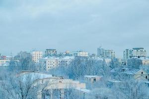vista de la ciudad en invierno. casas y árboles en la nieve. comienzo de la temporada de invierno. foto
