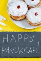 Happy Hanukkah. Jewish dessert Sufganiyot on yellow background. Symbols of religious Judaism holiday. Donuts, candles and gift. photo