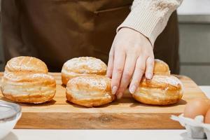 mujer prepara donas frescas con mermelada en la cocina de casa. cocina tradicional judía hanukkah sufganiyot. foto