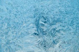 Frosty patterns on glass. Christmas background. Blue ice on winter window. photo