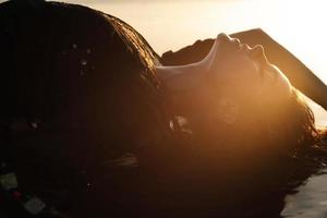 mujer sexy con túnica negra posa en la playa con arena negra foto