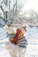 Young mother and her cute little son  playing peekaboo during sunny winter day photo