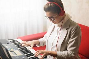 mujer joven músico tocando sintetizador en casa foto