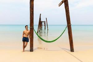 joven delgado y hamaca en la playa foto