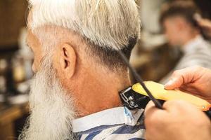 peluquero haciendo un corte de pelo elegante para un anciano foto