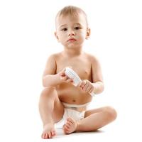 Little boy in diaper sitting and playing with brush. photo