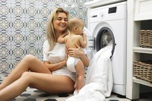 Mother and her little baby son are loading washing machine photo