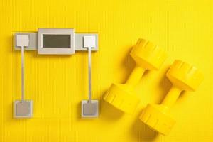 mancuernas amarillas y escala de peso en la alfombra de fitness foto