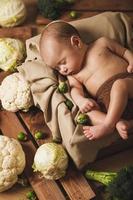 Little baby is lying in the box with a lot of different cabbages photo
