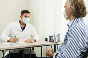 Doctor and middle aged male patient wearing prevention masks during consultation photo
