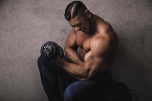 Massive bodybuilder doing biceps curl exercise with the dumbbell photo