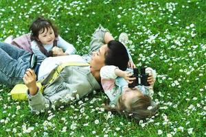 Happy family in a park. Mother and two daughter lying in chamomile field. photo