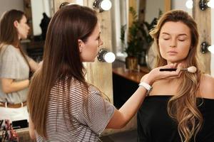Pofessional make-up artist and her working process during makeup routine for young and beautiful model photo