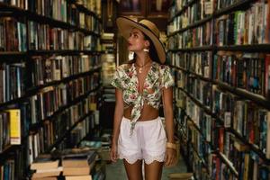bella chica con ropa elegante buscando un libro interesante en la librería antigua foto