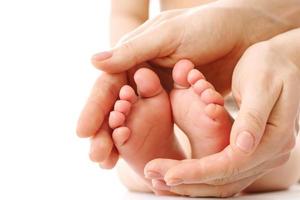 madre masajeando los pies y las plantas de los niños pequeños. foto