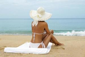 Woman in hat sitting on the beach photo