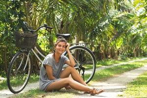 mujer joven y feliz con bicicleta en el jardín tropical