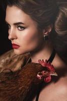 Gorgeous woman with beautiful makeup and hairstyle holding hen photo