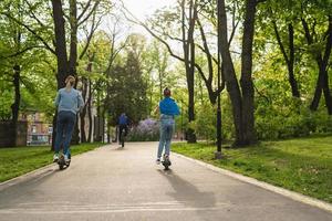 madre e hija montando scooters eléctricos en el parque de la ciudad foto