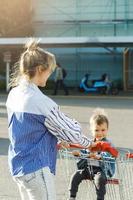 Young mother and her cute little son are having fun with shopping cart photo