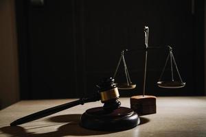 Justice and law concept.Male judge in a courtroom with the gavel, working with, computer and docking keyboard, eyeglasses, on table in morning light photo