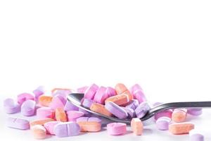 Closeup shot of spoon and pile of pills on white background. photo