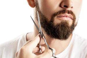 Man trimming his beard with a scissors photo
