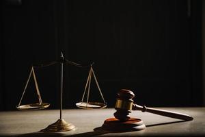 Justice and law concept.Male judge in a courtroom with the gavel, working with, computer and docking keyboard, eyeglasses, on table in morning light photo